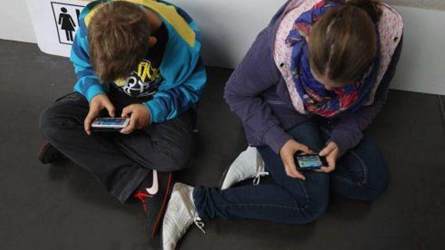 Un niño y una niña, con sus teléfonos.