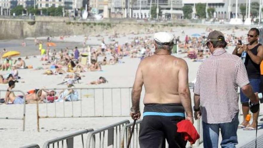 Paseo marítimo y bañistas en la playa de Riazor.