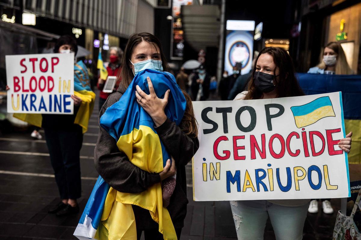 Una mujer con su bebé envuelto en una bandera de Ucrania participa en una protesta contra la guerra en el país, coincidiendo con el primer mes de conflicto, en una calle de Hong Kong.