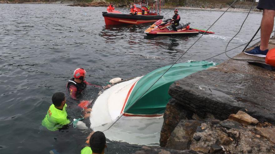 Buzos de los bomberos y socorristas tratan de voltear el barco tras remolcarlo al puerto.   | // CARLOS PARDELLAS