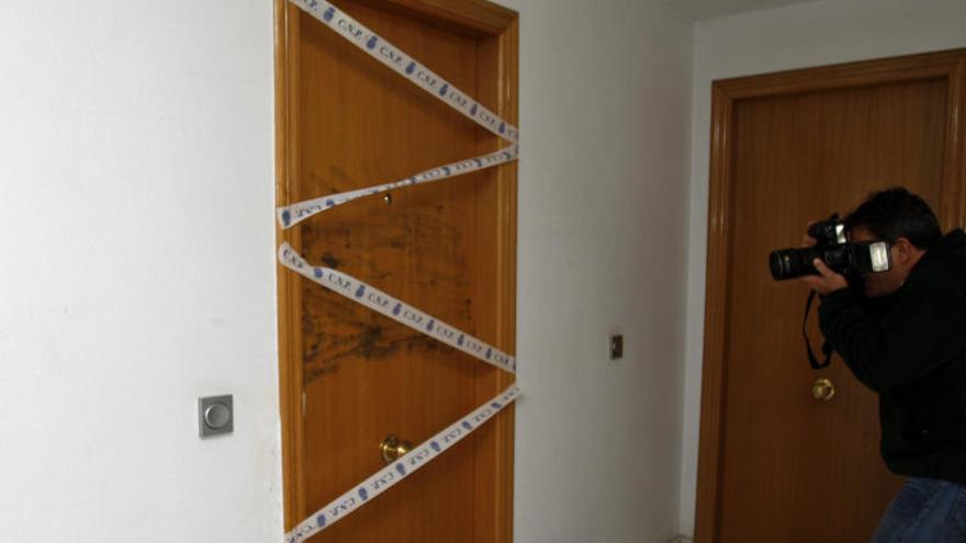 Un fotógrafo toma imágenes de la puerta de la vivienda del fallecido, un segundo piso.