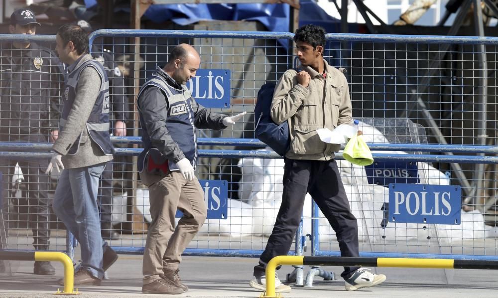 Policías escoltan a los refugiados que llegan al puerto de Dikili en Izmir