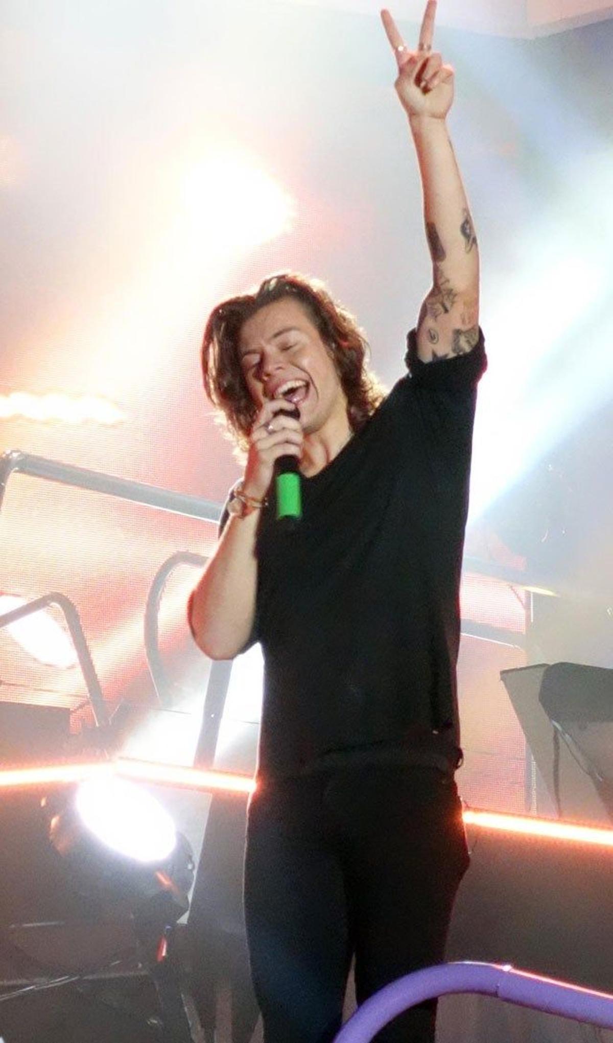 Harry Styles cantando mientras hace el signo de victoria en el concierto ofrecido en Sídney