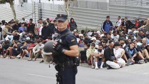 Un agente de la Policía Nacional, ante un grupo de migrantes en Ceuta.