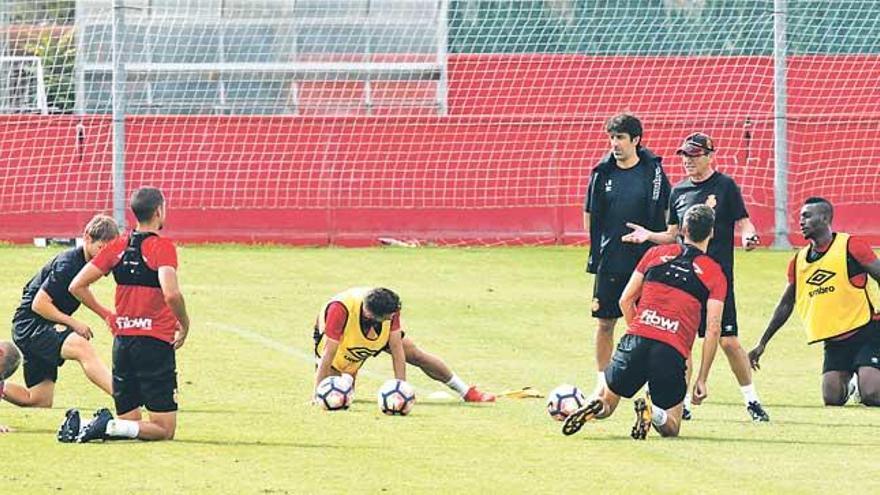 Fernando Vázquez, junto a Óscar Bruzón, conversa con sus jugadores sobre el césped.