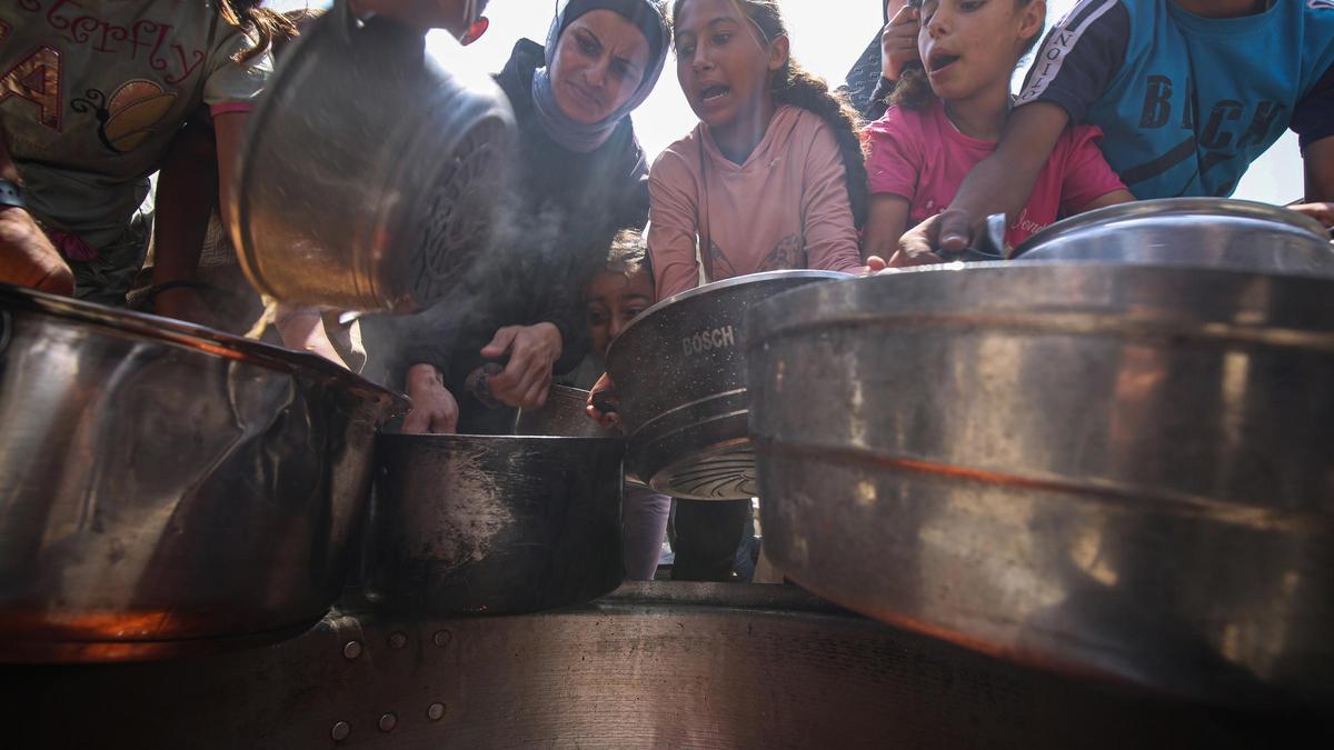 Un grupo de palestinos intenta obtener alimentos repartidos por una organización caritativa en la ciudad de Gaza, en el norte de la Franja de Gaza (archivo)
