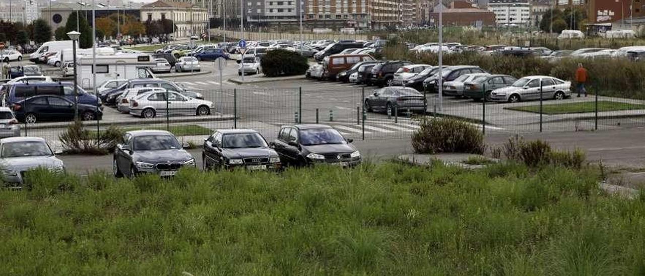 Una zona con maleza cerca de un aparcamiento, en el entorno del plan de vías.