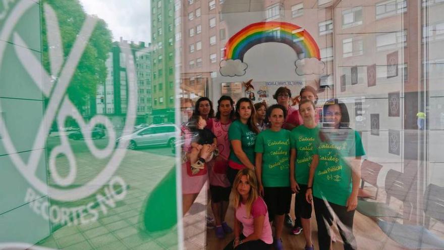 Un grupo de trabajadoras de las escuelas infantiles de Avilés, ayer, en El Quirinal, reflejadas en una puerta empapelada con carteles contrarios a los recortes de personal previstos por el Principado.