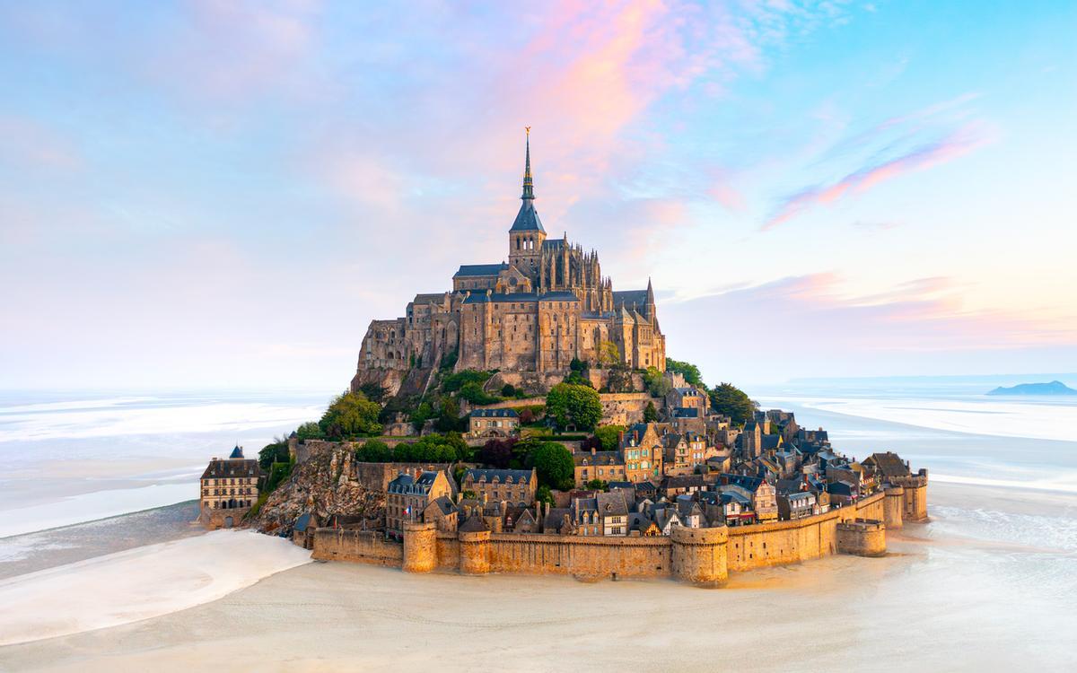 La isla del Mont Saint-Michel con abadía y pequeña ciudad a la luz del atardecer