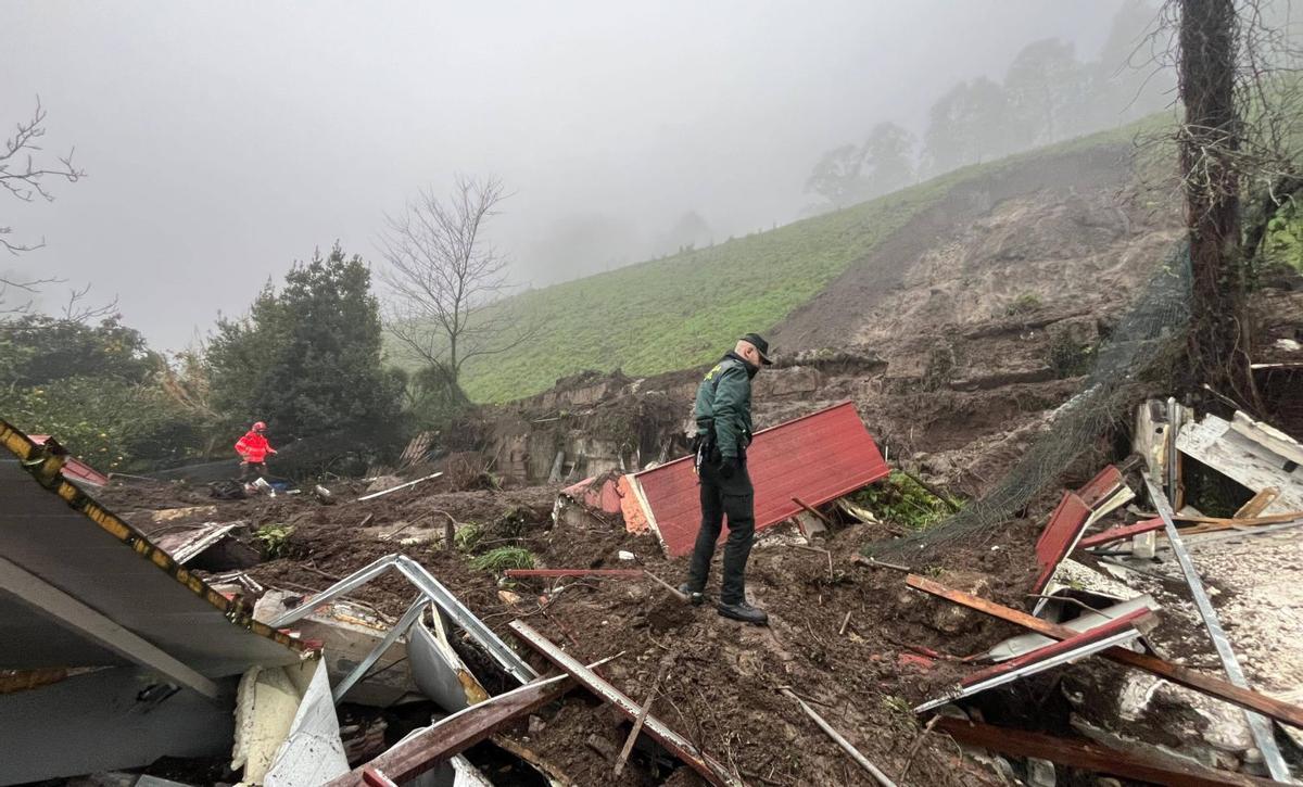 Un guardia civil y un miembro de emergencias, al poco tiempo del derrumbe del talud sobre la casa. | PABLO H. GAMARRA