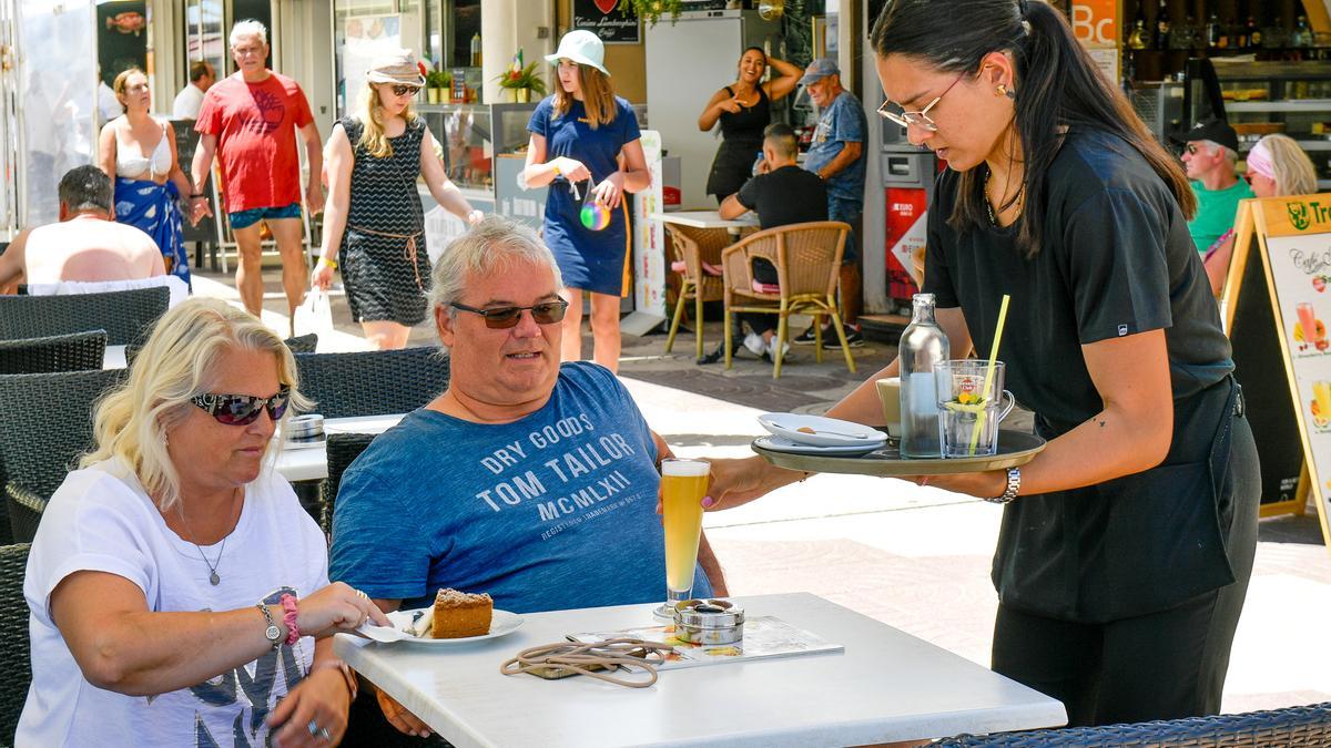 Una camarera sirve a dos turistas en un bar de Playa del Inglés, en Gran Canaria.