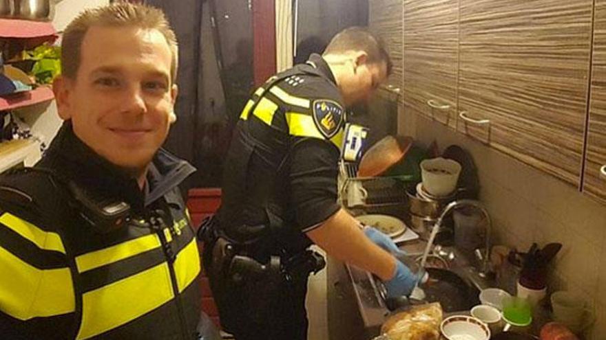 Los dos policías fregando los platos en casa de la mujer.