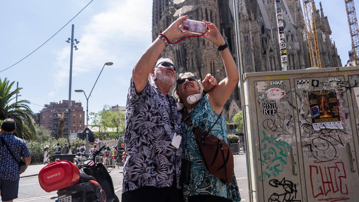 Una pareja de personas mayores se fotografía ante la Sagrada Família de Barcelona.