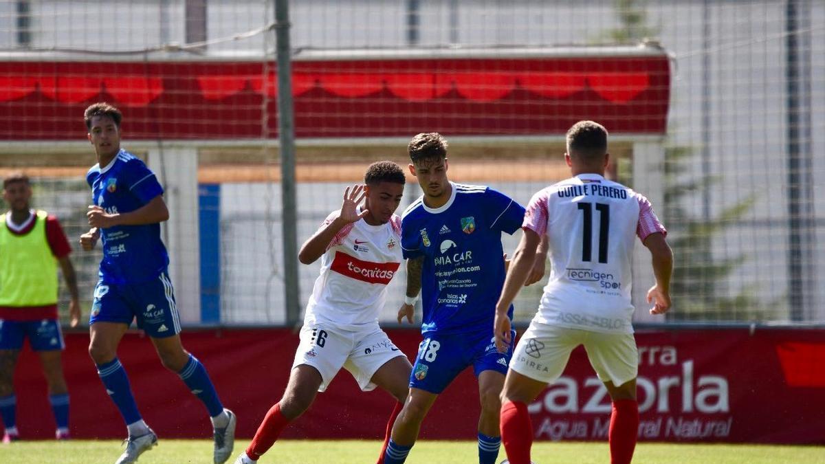 Carlos Galván controla el esférico entre dos rivales del 'Sanse'