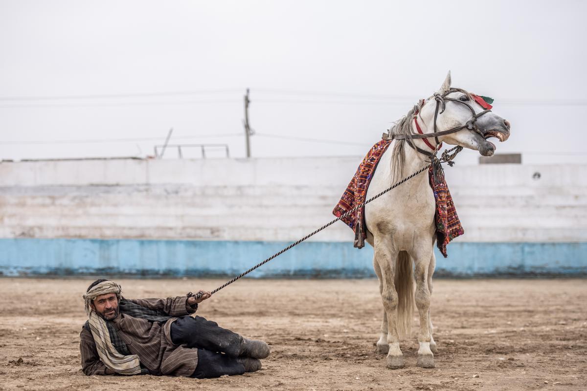 Jinetes afganos compiten en un deporte tradicional de Asia Central, en el que los jugadores montados a caballo intentan colocar una bolsa que se asemeja a un cadáver de cabra en una portería