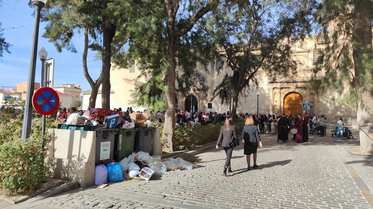 Contenedores sin recoger en el inicio del recorrido de una procesión infantil