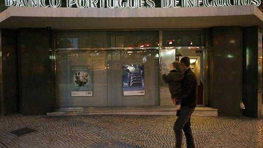 Un padre y su hijo pasan frente a una de las sucursales del Banco Portugués de Negocios.