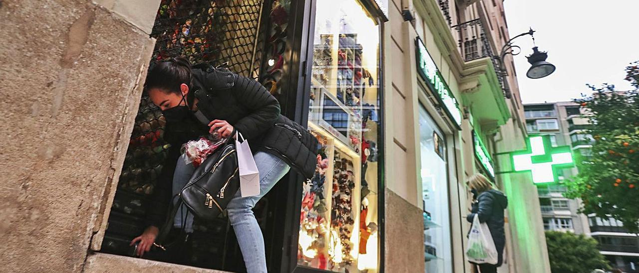 A la izquierda, una trabajadora cierra su comercio de la calle Jorge Juan de València. A la derecha, persianas bajadas pocos minutos después de las 18.00 horas. | F. CALABUIG