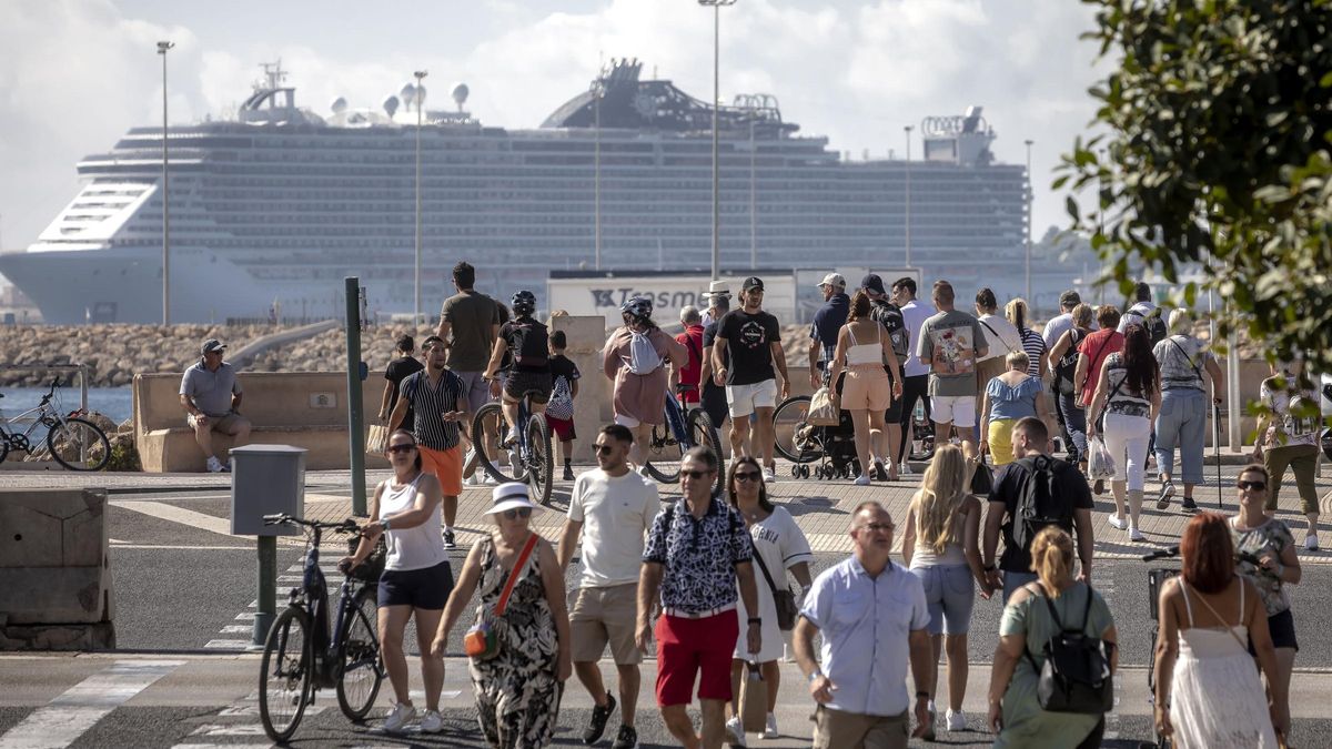 Turistas en el centro de Palma con un crucero de grandes dimensiones al fondo.