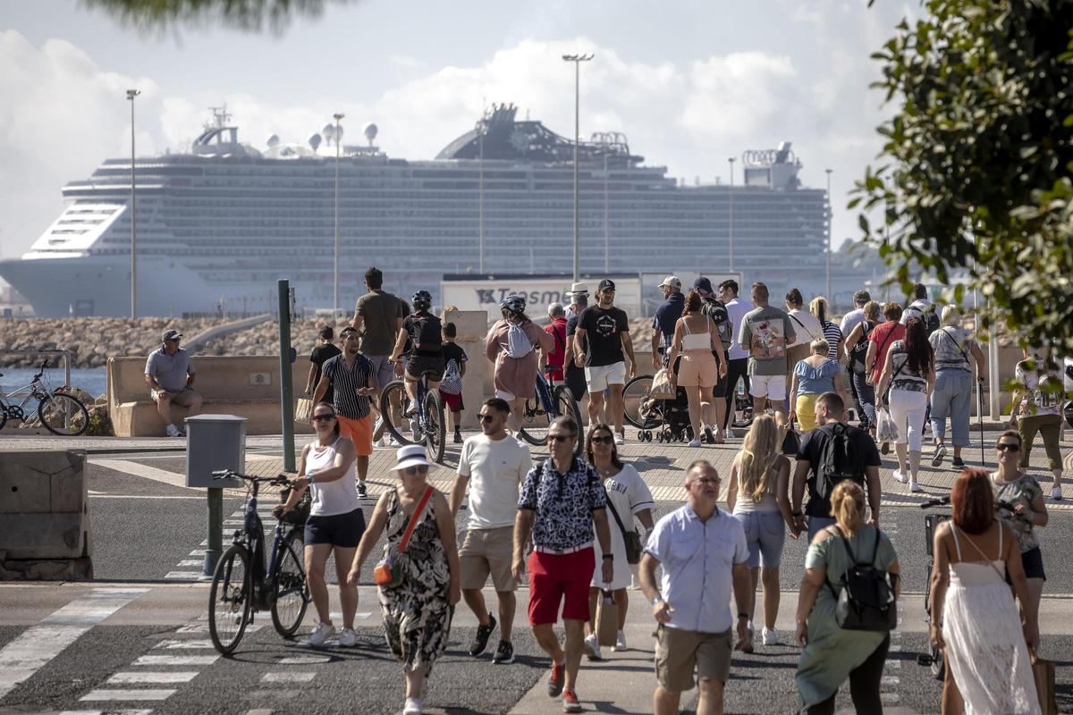 Turistas en el centro de Palma con un crucero de grandes dimensiones al fondo.