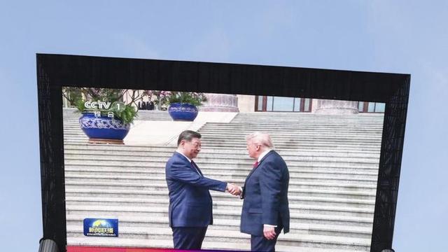 Una pantalla gegant mostra la salutació de Xi i Trump. | WU HAO / EFE