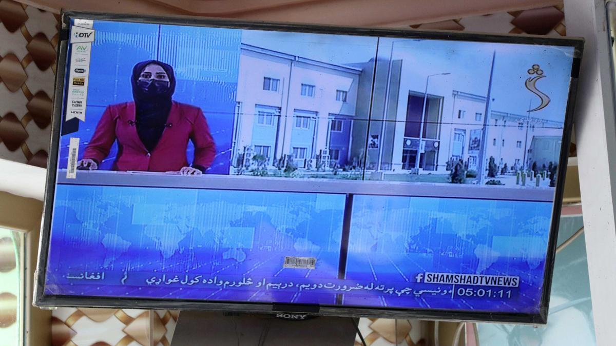 Una presentadora de televisión afgana con el rostro cubierto mientras explica las noticias