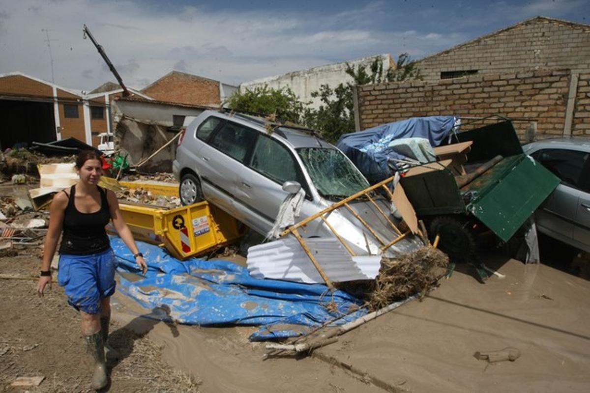 Una dona passa pel costat dels desperfectes ocasionats per les inundacions.