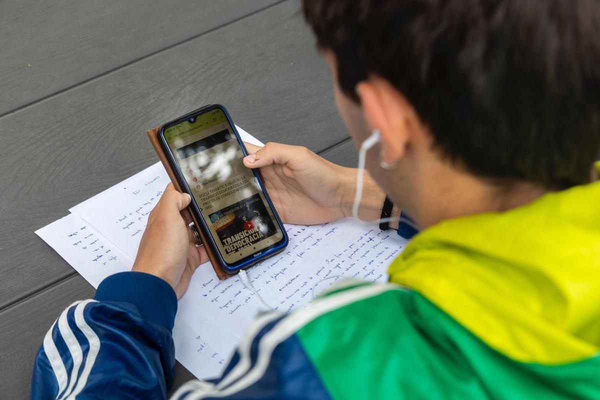 Un joven mira su teléfono móvil en la puerta del IES Campanar de València, antes de entrar a clase.
