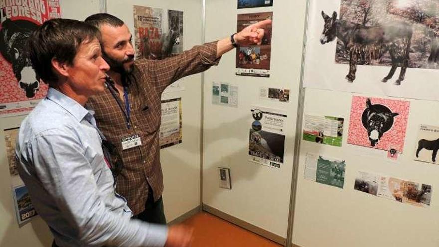 Dos personas comentan detalles del stand de raza asnal en Sevilla.