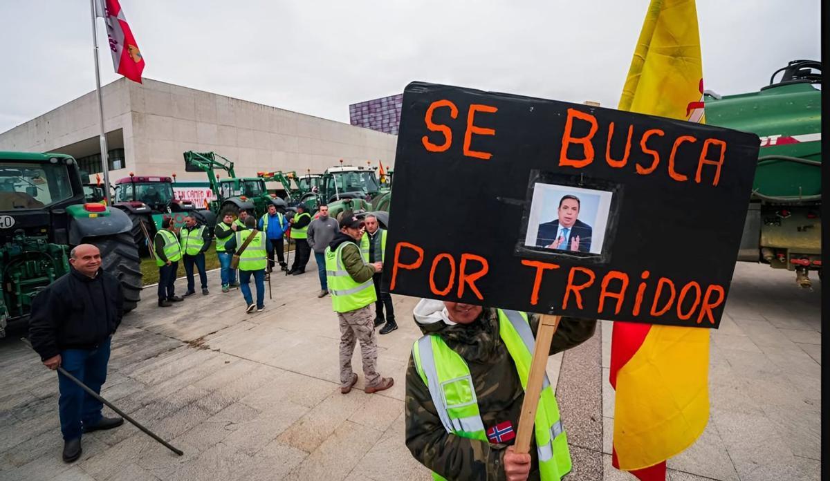 Un manifestante exhibe a las puertas de las Cortes un cartel con la imagen del ministro de Agricultura.  | DARÍO FERNÁNDEZ
