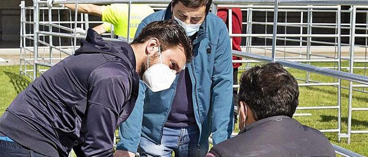 El Alcalde, en el centro, con dos técnicos, ayer, durante los preparativos de la feria, en el recinto ferial de Llanera. | LNE