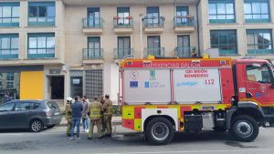 Bomberos junto al portal de la vivienda en la que se declaró el incendio.