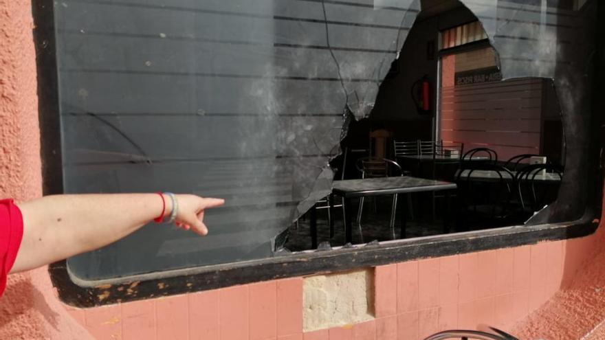 Una mujer muestra los daños en el cristal del bar.