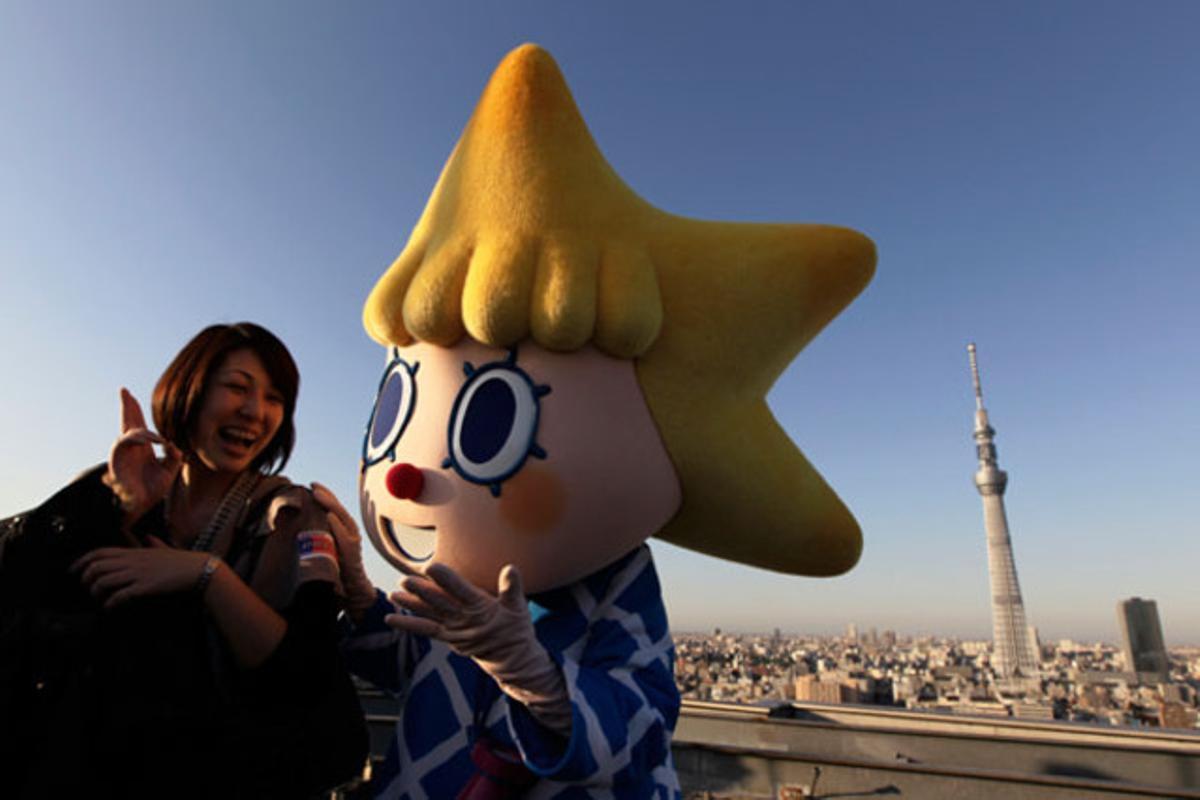 Una noia amb la mascota del Tokyo Sky Tree, la torre més alta del món, que es veu al fons de la imatge, a Tòquio (Japó).