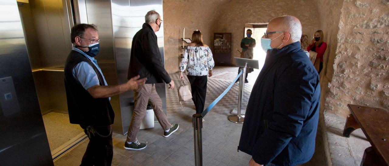 Turistas en el túnel que da entrada a los ascensores y saliendo de uno de los elevadores, ayer. | JOSE NAVARRO