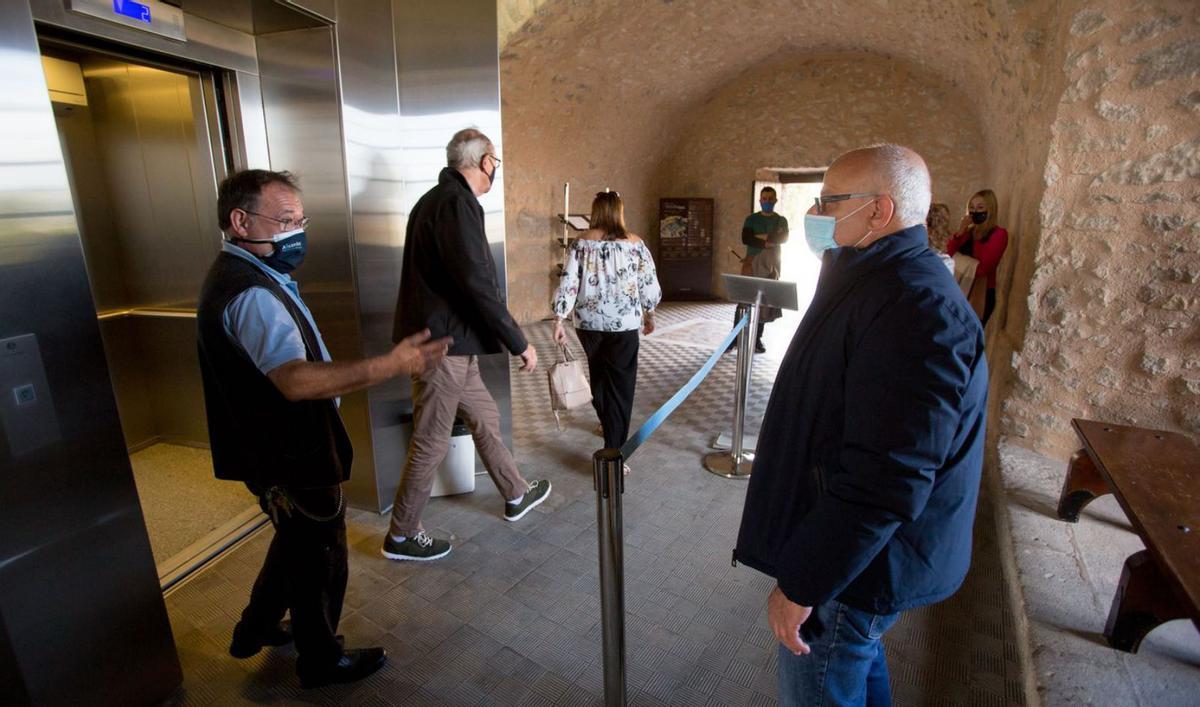 Turistas en el túnel que da entrada a los ascensores y saliendo de uno de los elevadores, ayer. | JOSE NAVARRO