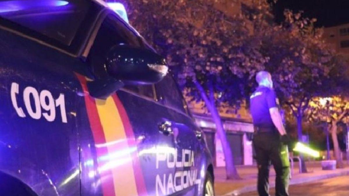 Un agente de la Policía Nacional unto al coche patrulla.