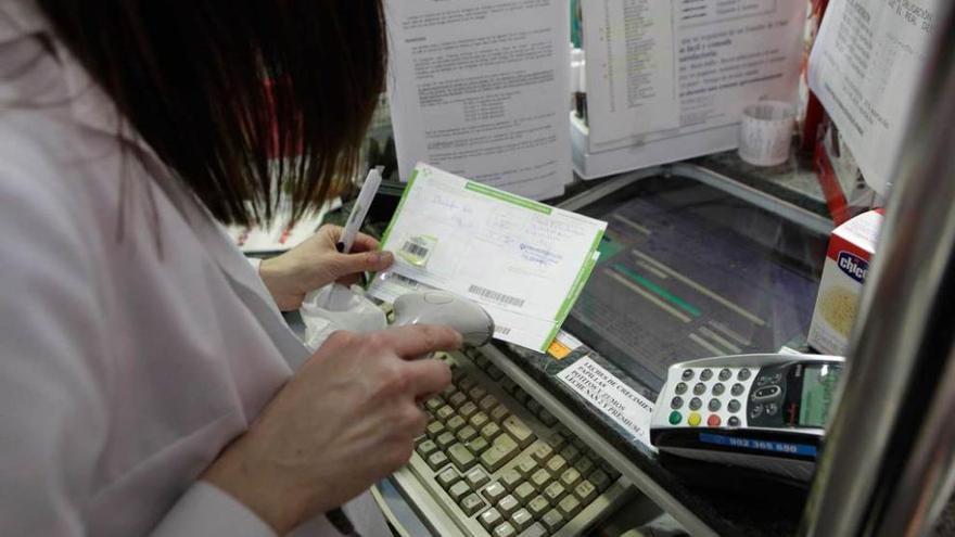 Una trabajadora de una farmacia procesa una receta.