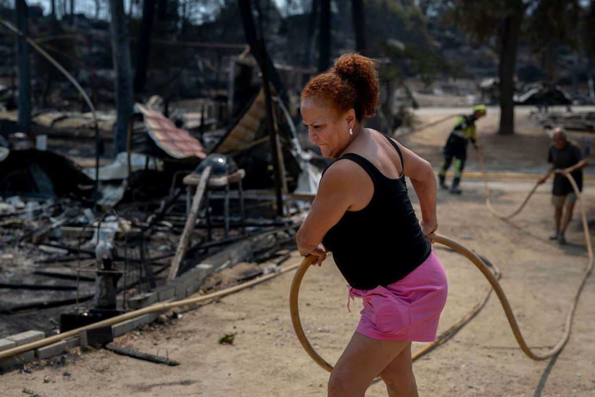 Un trabajador ayuda a mover una manguera de agua en el campamento de Pantano de Burguillo después de un incendio forestal en El Barraco, España, el martes 28 de julio de 2026.