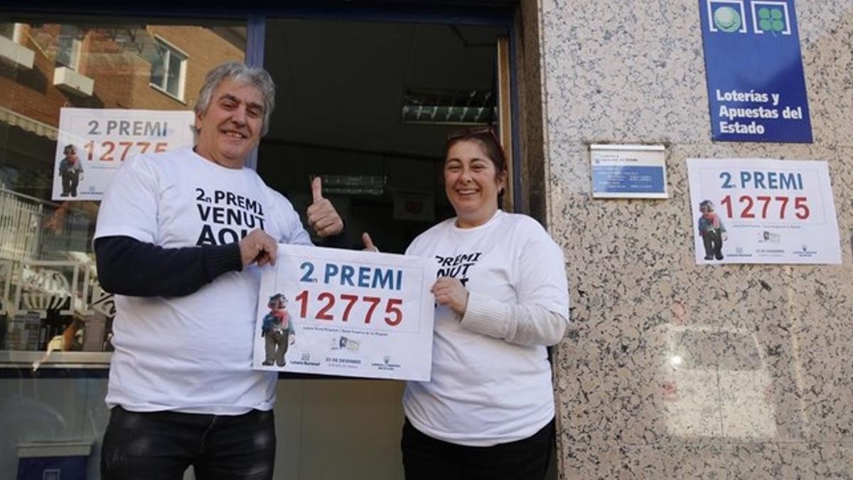 Siscu Flores y Carmen Gordillo, propietarios de la administración agraciada con parte del segundo premio del Gordo, ante la puerta de su negocio, en Santa Perpètua de la Mogoda.ación agraciada en Santa Perpètua de la Mogoda.