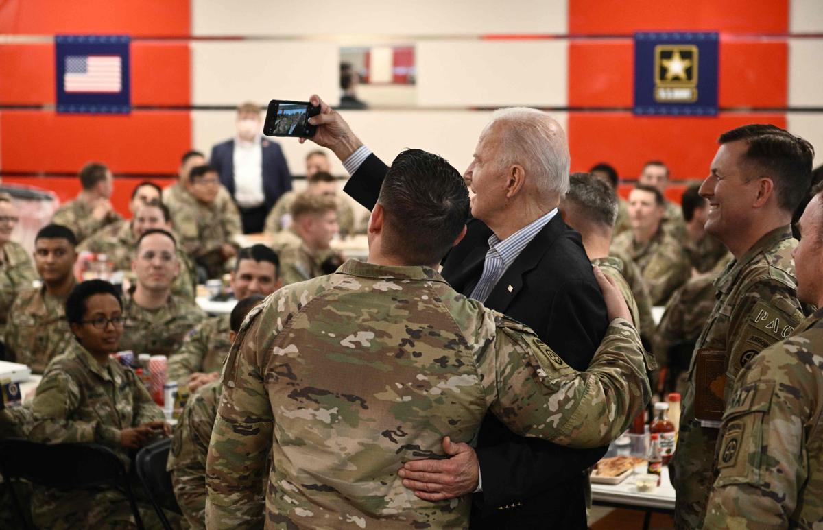 El presidente de EE. UU., Joe Biden (centro), se toma una selfie mientras se encuentra con miembros del servicio de la 82.a División Aerotransportada, que contribuyen junto con los aliados polacos a la disuasión en el flanco oriental de la Alianza, en la ciudad de Rzeszow, en el sureste de Polonia, a unos 100 kilómetros de la frontera con Ucrania