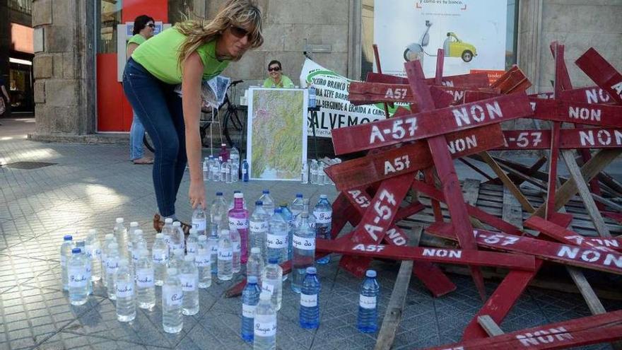 Las botellas con agua de A Fracha, junto a las cruces contra la autovía. // Rafa Vázquez