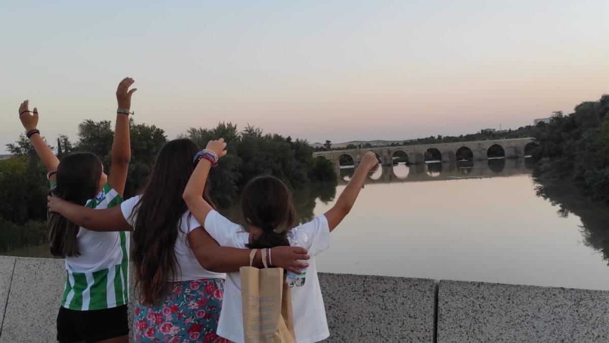 Tres menores tuteladas contemplan el río Guadalquivir desde el Puente Romano.