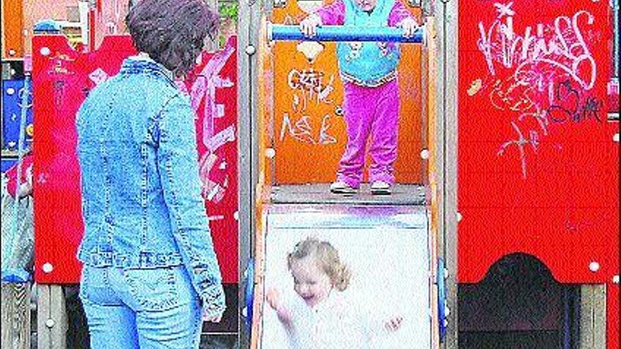 Una madre vigila a dos niñas mientras juegan en el parque de Mieres.