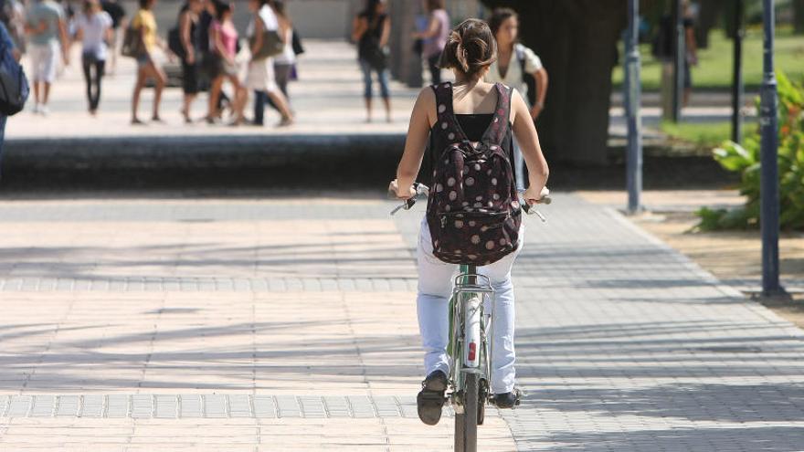 Una joven desplazándose en bicicleta por el campus de la Universidad de Alicante.