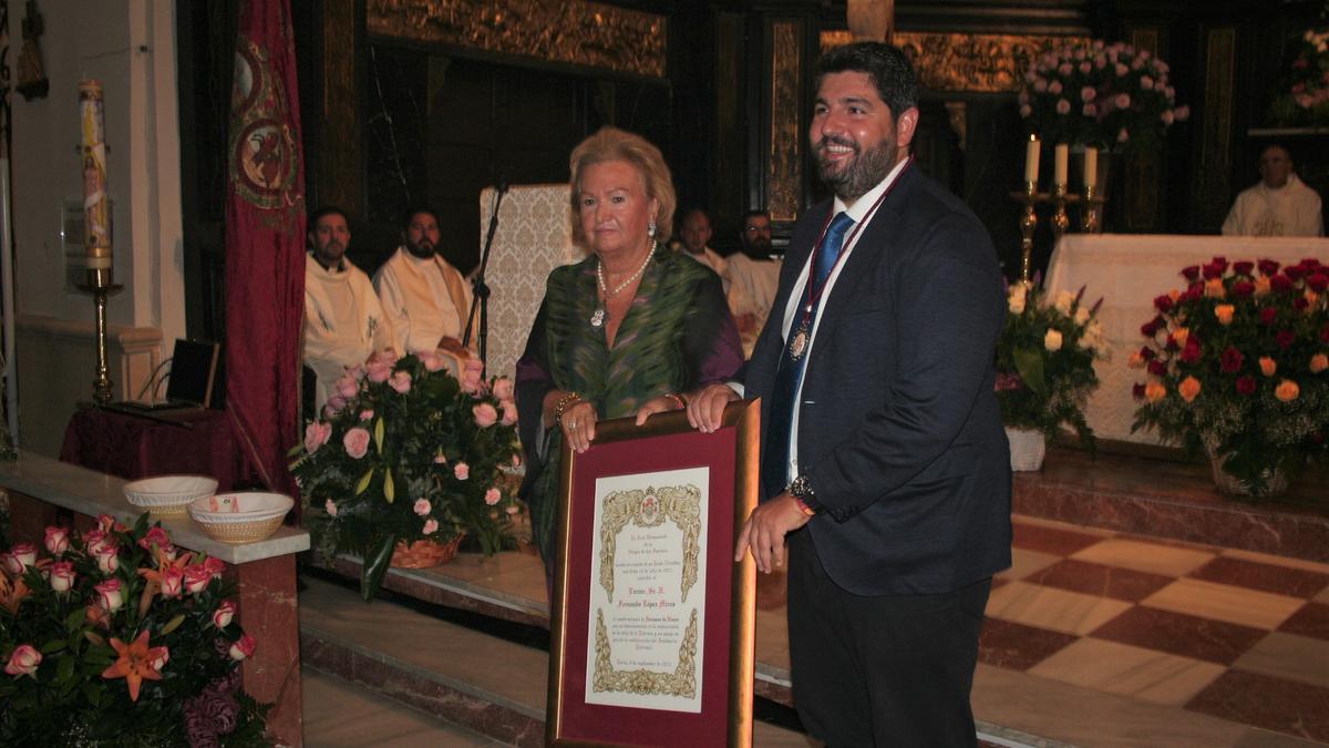 La expresidenta de la Hermandad de la Virgen de las Huertas, Isabel Jiménez, entregaba al presidente de la Comunidad Autónoma, Fernando López Miras, el título honorífico de Hermano Mayor de la Patrona.