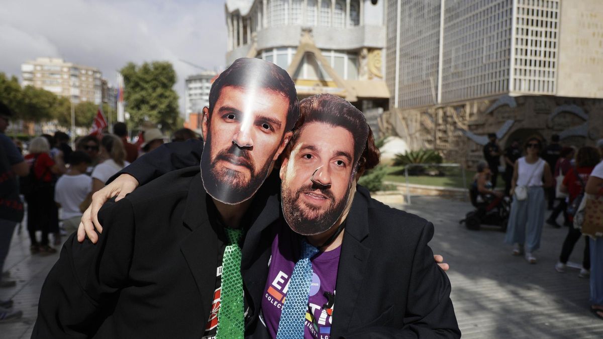 Dos protestantes, con las caretas de José Ángel Antelo y López Miras, junto a la Asamblea Regional.