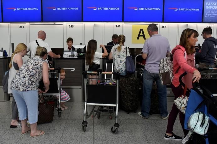 People wait with their luggage at the British ...