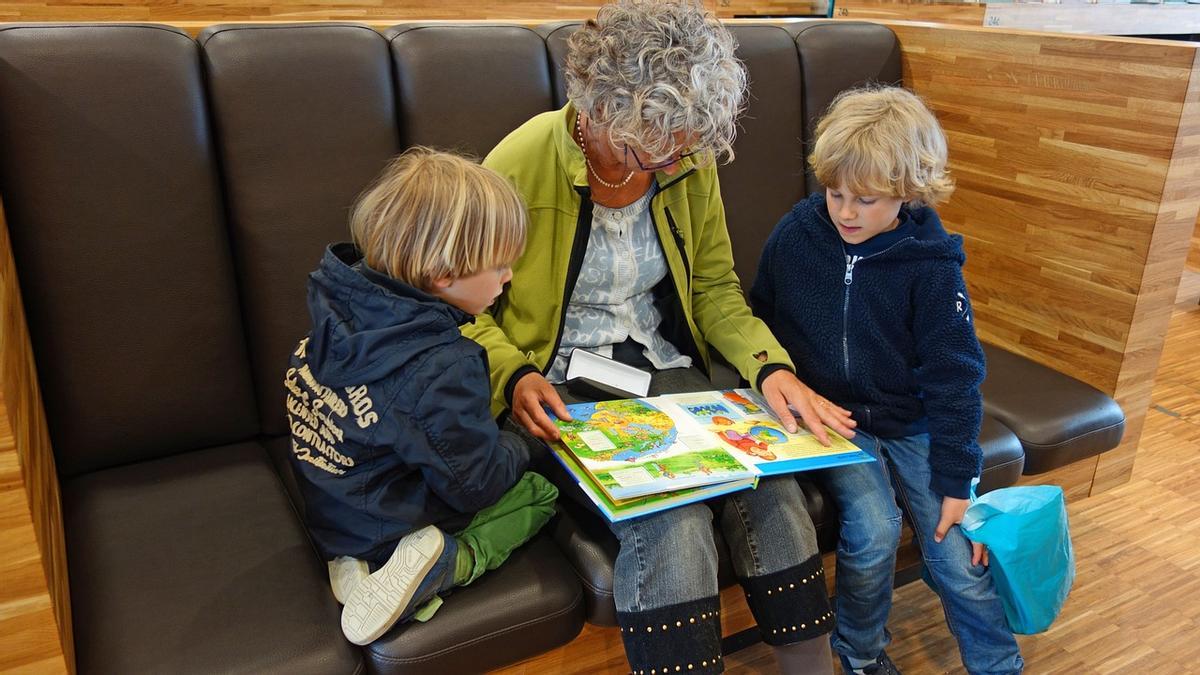 Una àvia llegint un conte amb els seus nets, en una imatge d'arxiu
