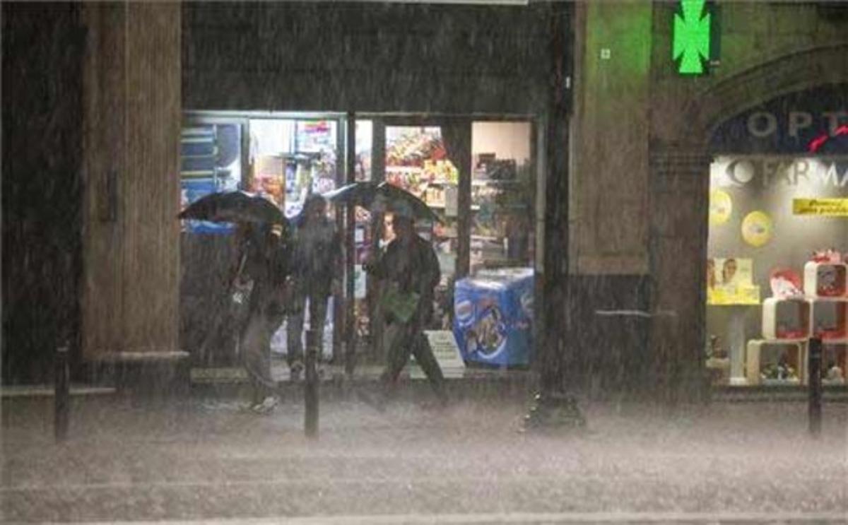 Lluvia torrencial frente a algunos comercios en Vía Laietana. Durante la tormenta se han registrado hasta 47 litros en la estación meteorológica del Raval.